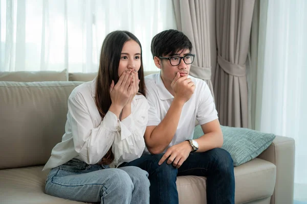 Asian Couple man and woman watching and enjoying terror tv movie