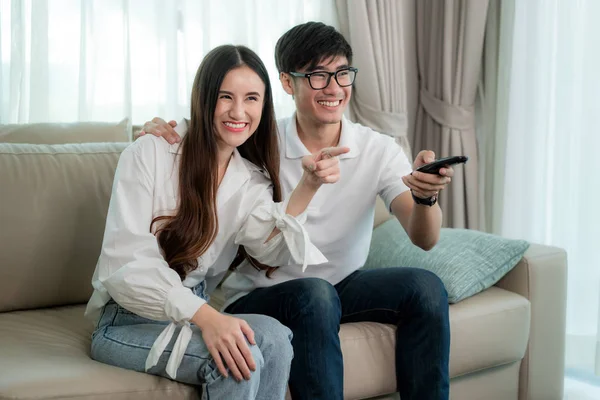 Asiático jovem casal amoroso sentado e assistindo TV e sorriso quando — Fotografia de Stock