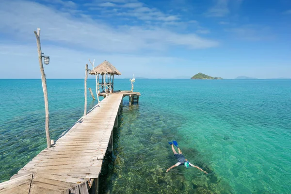 Tourists snorkel in crystal turquoise water near tropical resort — Stock Photo, Image