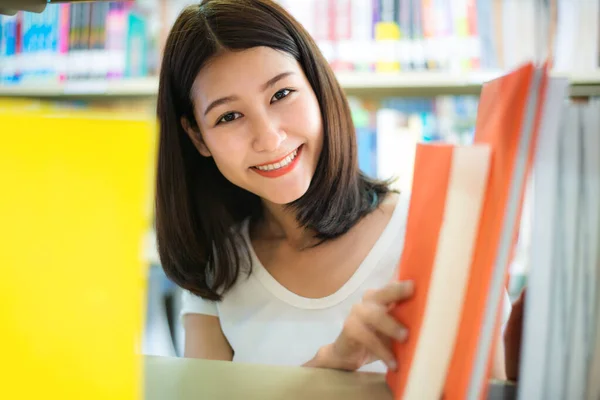 Cheerful female Asian student girl reading book during break bet — Stock Photo, Image