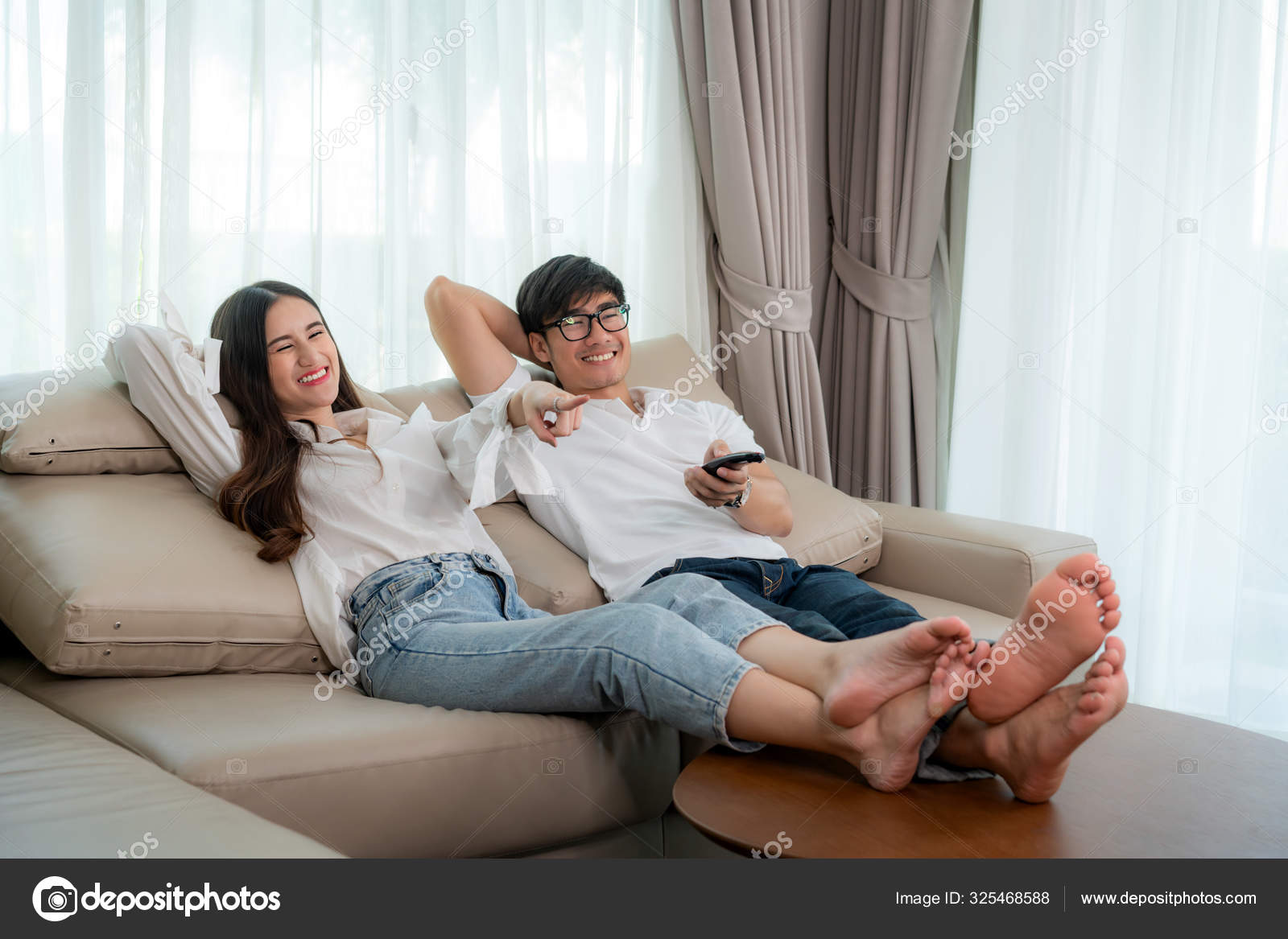 Asian Couple Lifestyle, Man Holding Remote Control And Woman Wat.