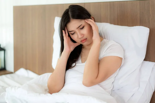Привлекательная молодая азиатка просыпается на кровати, держа свою ха — стоковое фото