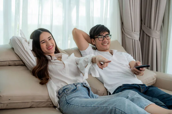 Asiático pareja estilo de vida, hombre celebración de control remoto y mujer wat — Foto de Stock