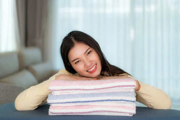 Glad asiatisk kvinna på rena vikta kläder hemma. Vacker — Stockfoto