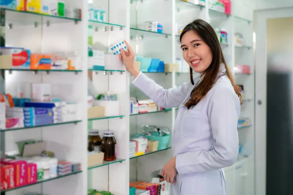 Asiatisk ung kvinna farmaceut med en härlig vänlig leende pick c — Stockfoto