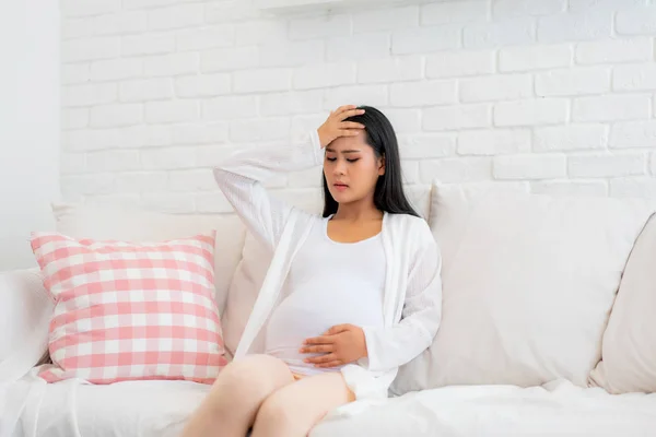 Wanita hamil muda dengan sakit kepala duduk di sofa di roo hidup — Stok Foto