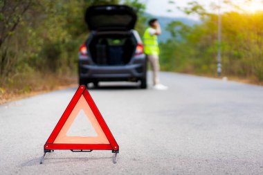 Breakdown triangle sign on road with worried Asian man talking b