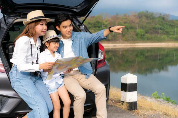 Portrait of Asian family sitting in car with father pointing to