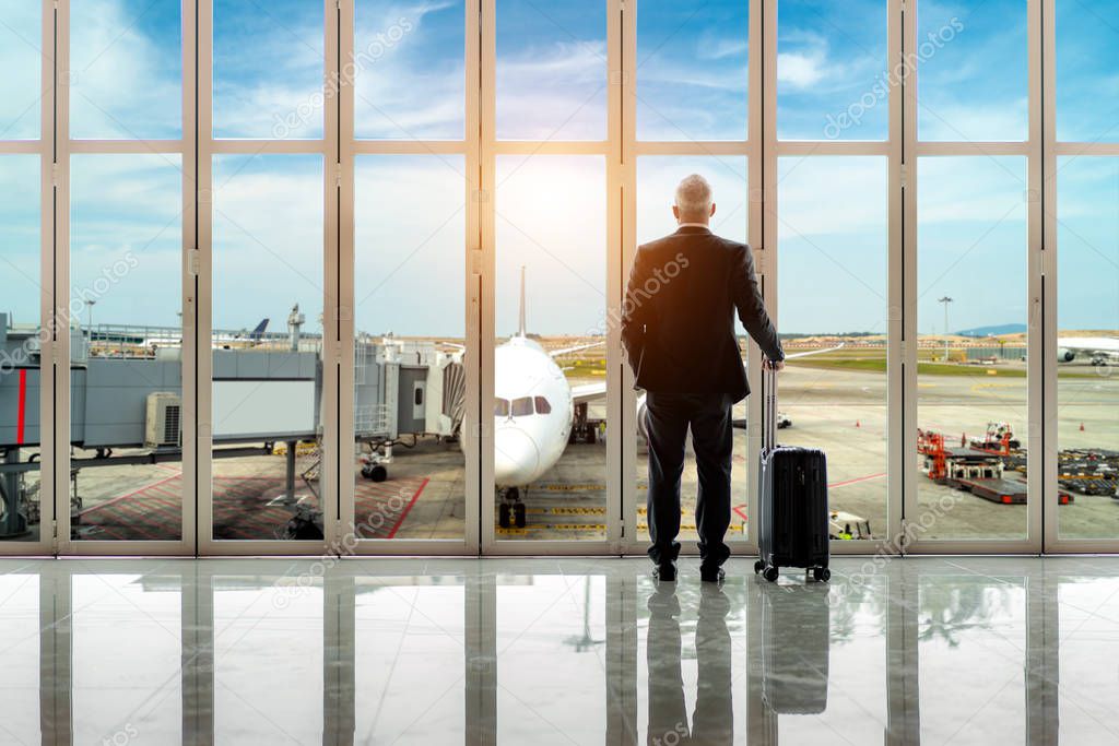 Businessman  standing together with baggage near the window at t