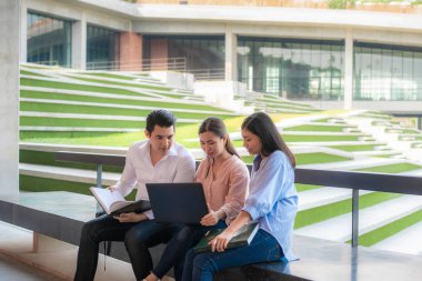 Üç Asyalı öğrenci üniversitede laptopla sınav hazırlığı, sunum, çalışma ve çalışma konularını tartışıyor. Eğitim, Öğrenim, Öğrenci, Kampüs, Üniversite, Yaşam Tarzı Konsepti.