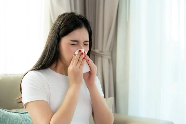 Asian woman sick and sad with sneezing on nose and cold cough on tissue paper because influenza and weak or virus bacteria from dust weather or smoke for medical