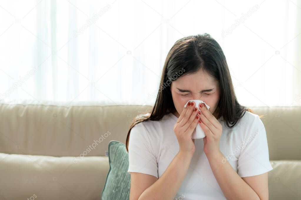 Asian woman sick and sad with sneezing on nose and cold cough on tissue paper because influenza and weak or virus bacteria from dust weather or smoke for medical
