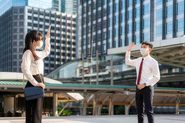 Asian business man and woman greet and say hello with business colleague and wearing mask standing distance of 1 meter distance protect from COVID-19 viruses for social distancing  for infection risk and disease prevention measures.