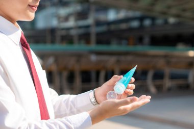 Şehirdeki Novel Coronavirus (2019-nCoV) ya da COVID-19 'a karşı el dezenfektanı kullanarak Asyalı iş adamını kapatın. Antiseptik.