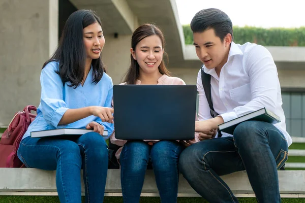 Three Asian students are discussing about exam preparation, presentation, study, study for test preparation with laptop in University. Education, Learning, Student, Campus, University, Lifestyle concept.