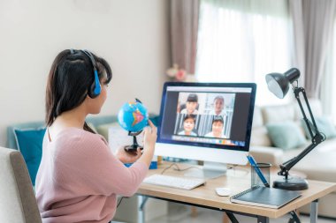 Video konferansında coğrafya öğretmenliği yapan Asyalı kadın öğretmen e-öğrenim ve neşeli ilkokul öğrencisi dünya, evde eğitim ve uzak öğrenim, çevrimiçi, eğitim ve İnternet 'e bakıyor.