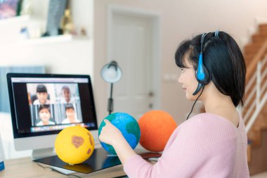 Asyalı kadın öğretmen video konferansında e-öğrenme ve neşeli ilkokul öğrencisi ile güneş sistemi öğretiyor. Dünya, ev eğitimi ve uzaklık öğrenimi, çevrimiçi, eğitim ve İnternet 'e bakıyor.
