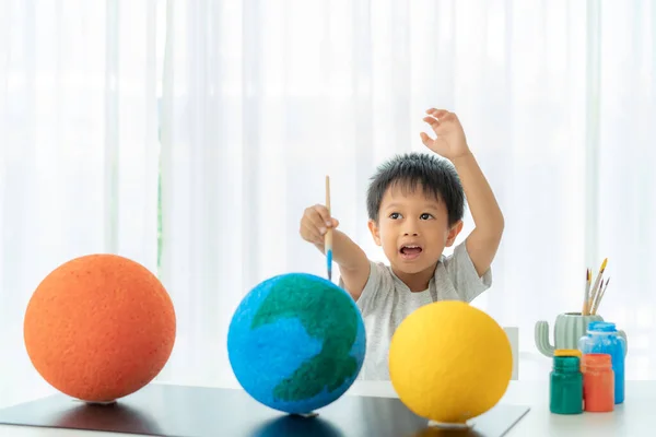 Asian preschool student boy painting the moon learning about the solar system at home, Homeschooling and distance learning