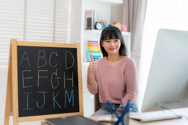Asian woman teacher teaching English alphabet via video conference e-learning to elementary school student, Homeschooling and distance learning ,online ,education and internet.