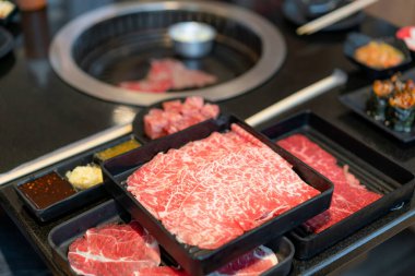 Kaliteli çiğ çiğ wagyu eti, domuz eti, suşi ve sos gibi ham et tabakları. Geleneksel Japon barbekü stili Yakiniku olarak da bilinir..
