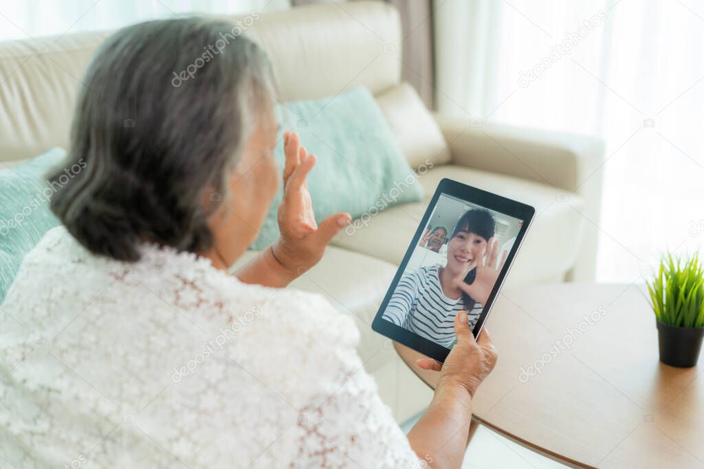 Asian elderly woman virtual happy hour meeting and talking online together with her daughter in video conference with tablet for a online meeting in video call for social distancing
