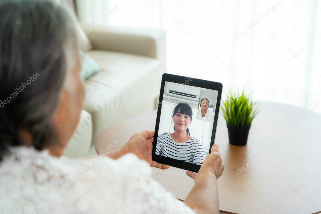 Asian elderly woman virtual happy hour meeting and talking online together with her daughter in video conference with tablet for a online meeting in video call for social distancing