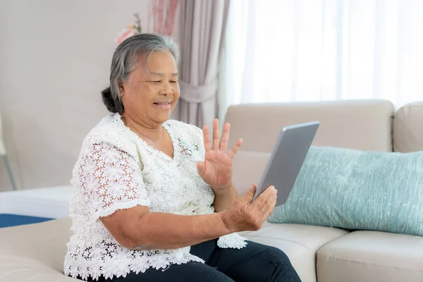 Asian elderly woman virtual happy hour meeting and talking online together with her daughter in video conference with digital tablet for a online meeting in video call for social distancing