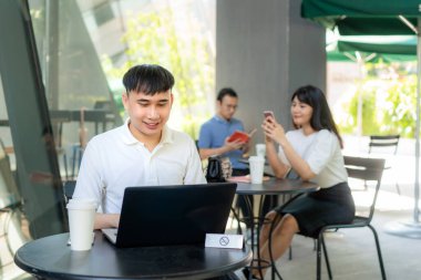 Asya 'lı genç adam ve kadın, 1,5 metre uzaklıktaki her masada bir kişi oturuyor. Kahve kafesinde enfeksiyon riskine karşı sosyal mesafeler için COVID-19 virüslerinden korunuyor.