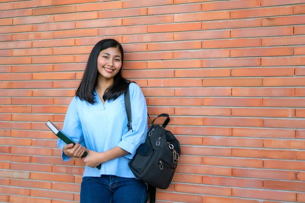 Asiático Sorrindo Mulher Estudante Segurando Livro Posando Fundo Tijolo Campus — Fotografia de Stock