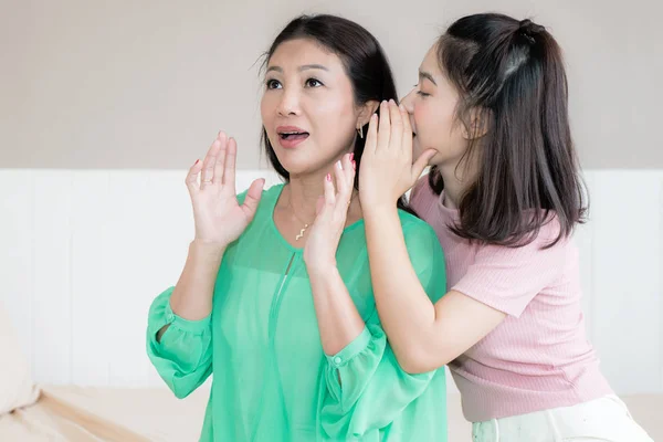 Asian teenage girl is whispering to her mothers ear — listening, female -  Stock Photo | #160972432