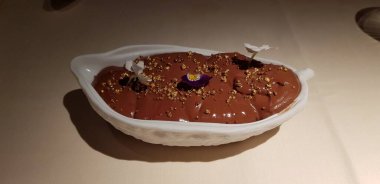 Kakaonun meyvesini taklit eden bir kabın içinde nefis bir çikolata portresi sunuyor.