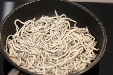 Siyah tavada sarımsaklı bebek yılan balıkları.