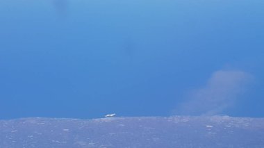 Sahilde uçan bir uçağın havadan manzarası daha yüksek uçan başka bir uçaktan görülüyor.