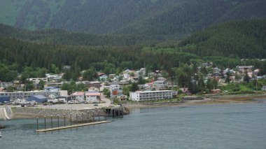 Dağların eteklerindeki ahşap evler Juneau, Alaska, ABD 'de deniz kenarında.