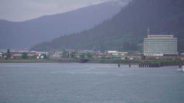 Dağların eteklerindeki ahşap evler Juneau, Alaska, ABD 'de deniz kenarında.