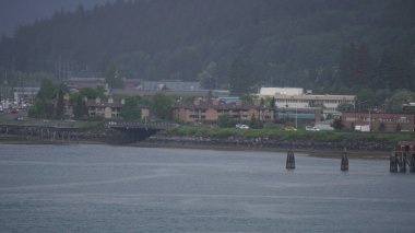 Dağların eteklerindeki ahşap evler Juneau, Alaska, ABD 'de deniz kenarında.