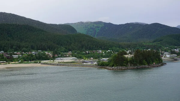 Dağların eteklerindeki ahşap evler Juneau, Alaska, ABD 'de deniz kenarında.
