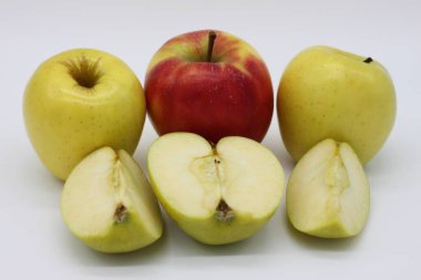 Altın ve kırmızı elmalar bir bütün ve beyaz arkaplanda çeyreklikler halinde kesilmiş.