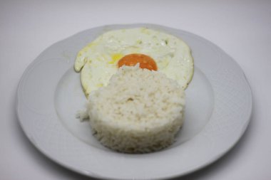 Sahanda yumurta ve beyaz pirinç beyaz arka planda izole edilmiş.