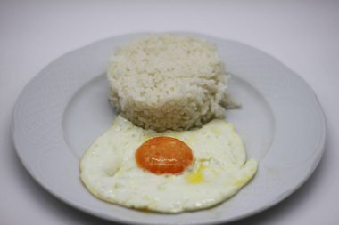 Sahanda yumurta ve beyaz pirinç beyaz arka planda izole edilmiş.