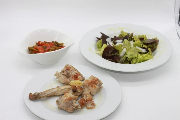 healthy menu of salad, rabbit stew and roasted red and green peppers