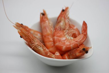 Beyaz arka planda izole edilmiş bir kasede pişmiş karidesler.