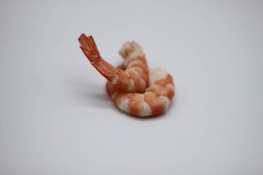 Pembe pişmiş ve soyulmuş karides kuyrukları beyaz arka planda izole edilmiş.
