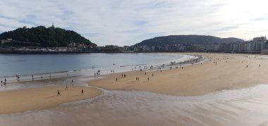 İnsanlar Donostia San Sebastian 'daki La Concha plajında geziniyorlar.