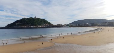 İnsanlar Donostia San Sebastian 'daki La Concha plajında geziniyorlar.
