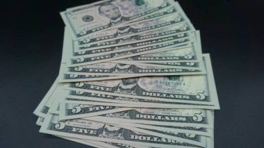 Siyah arka planda beş dolarlık banknotlar