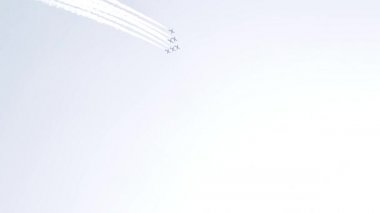 Five fighter jets in the blue sky. White color. A general plan. Aerobatic figures. Airshow. 14 seconds