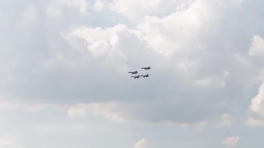 Mavi gökyüzünde dört savaş uçağı. Genel bir plan. Aerobatik figürler. Hava gösterisi. 10 saniye.