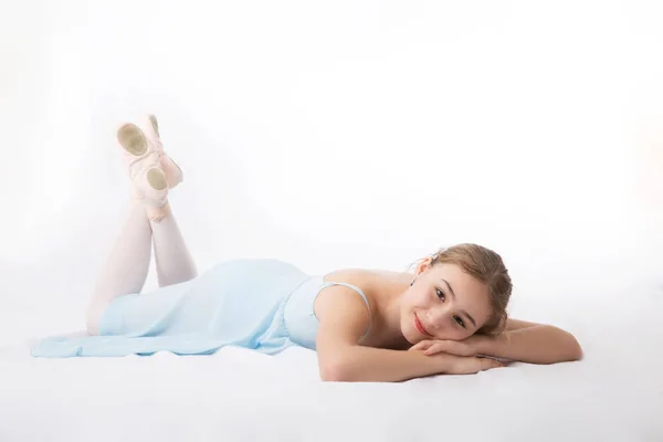 Chica en vestido azul descansando en el suelo sobre un fondo blanco — Foto de Stock