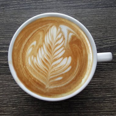 Bir fincan kahve latte sanat üstten görünüm ahşap arka plan üzerinde.